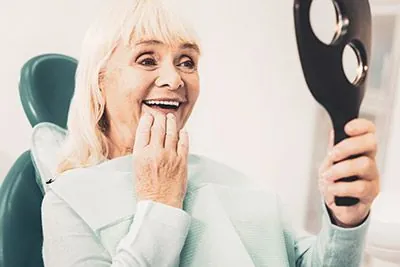 woman looking in the mirror at her new dental implants