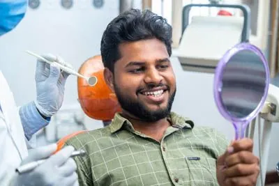 man looking in a mirror after a root canal helped relieve his tooth pain